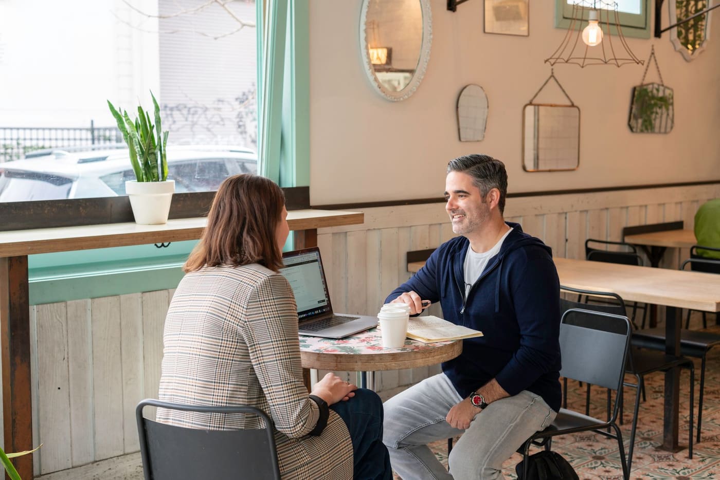 Two adults talking over coffee at a table in a modern cafe