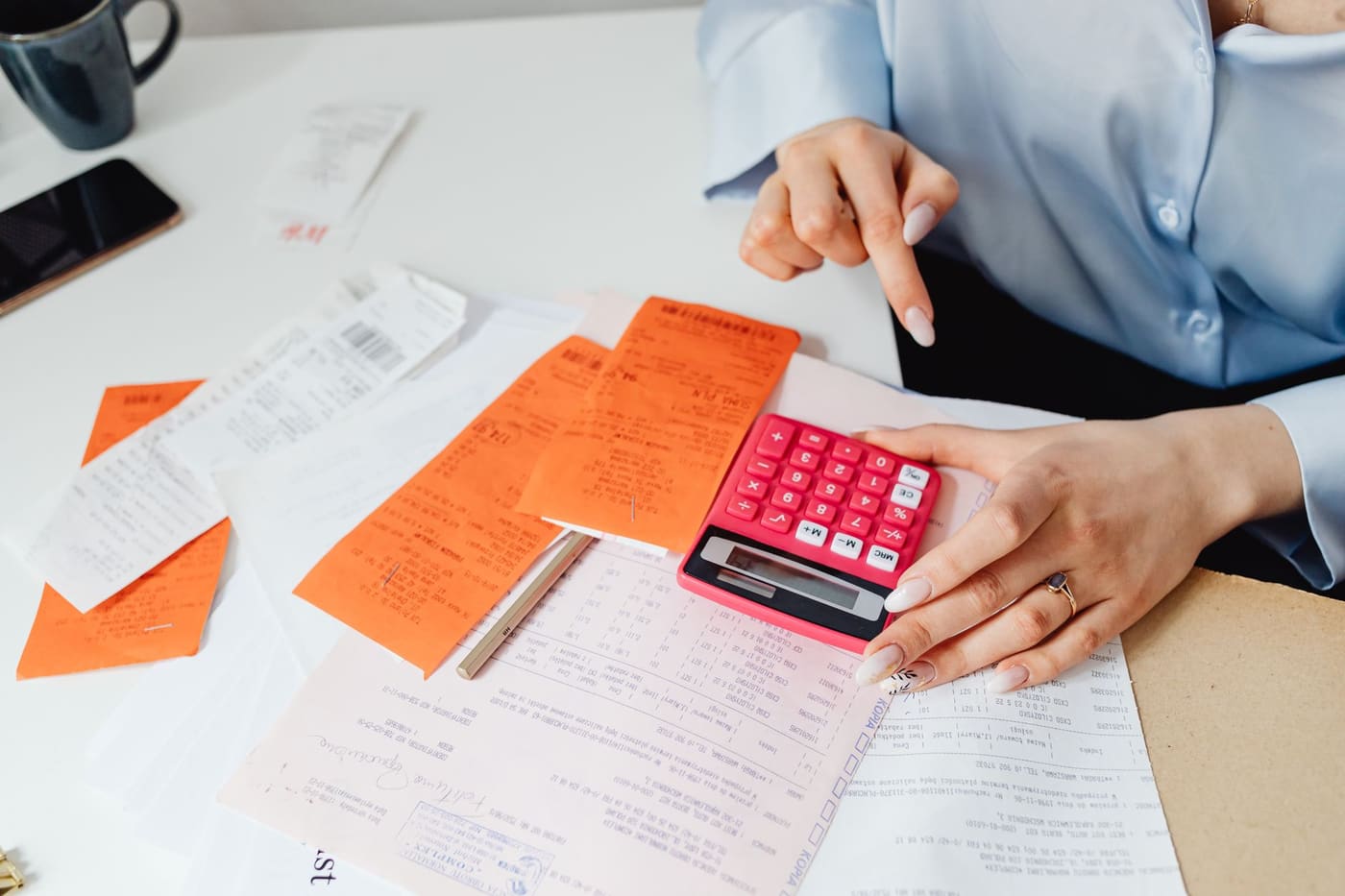 A calculator beside receipts and paperwork on a desk