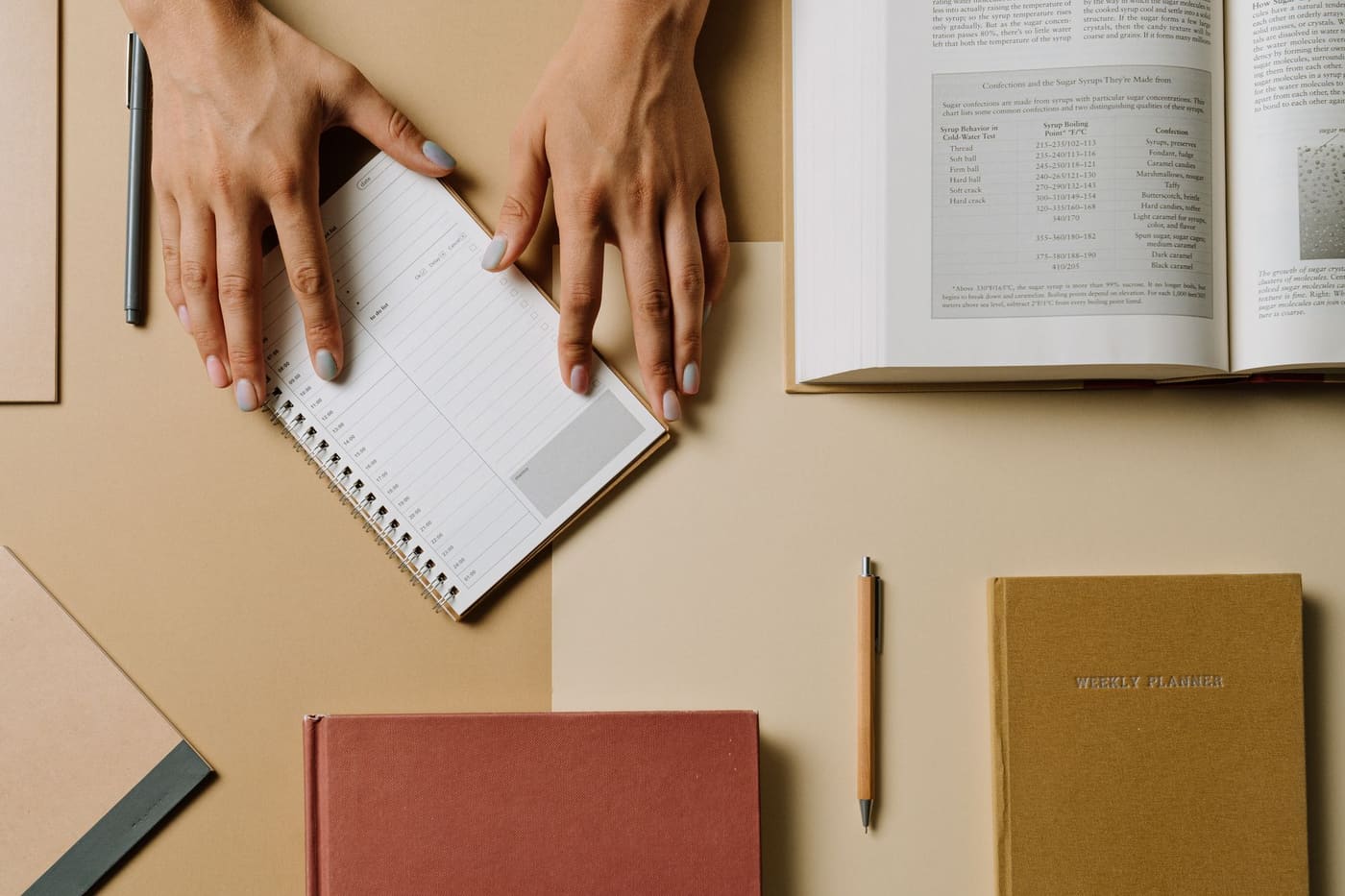 Hands arranging a notebook and books on a desk