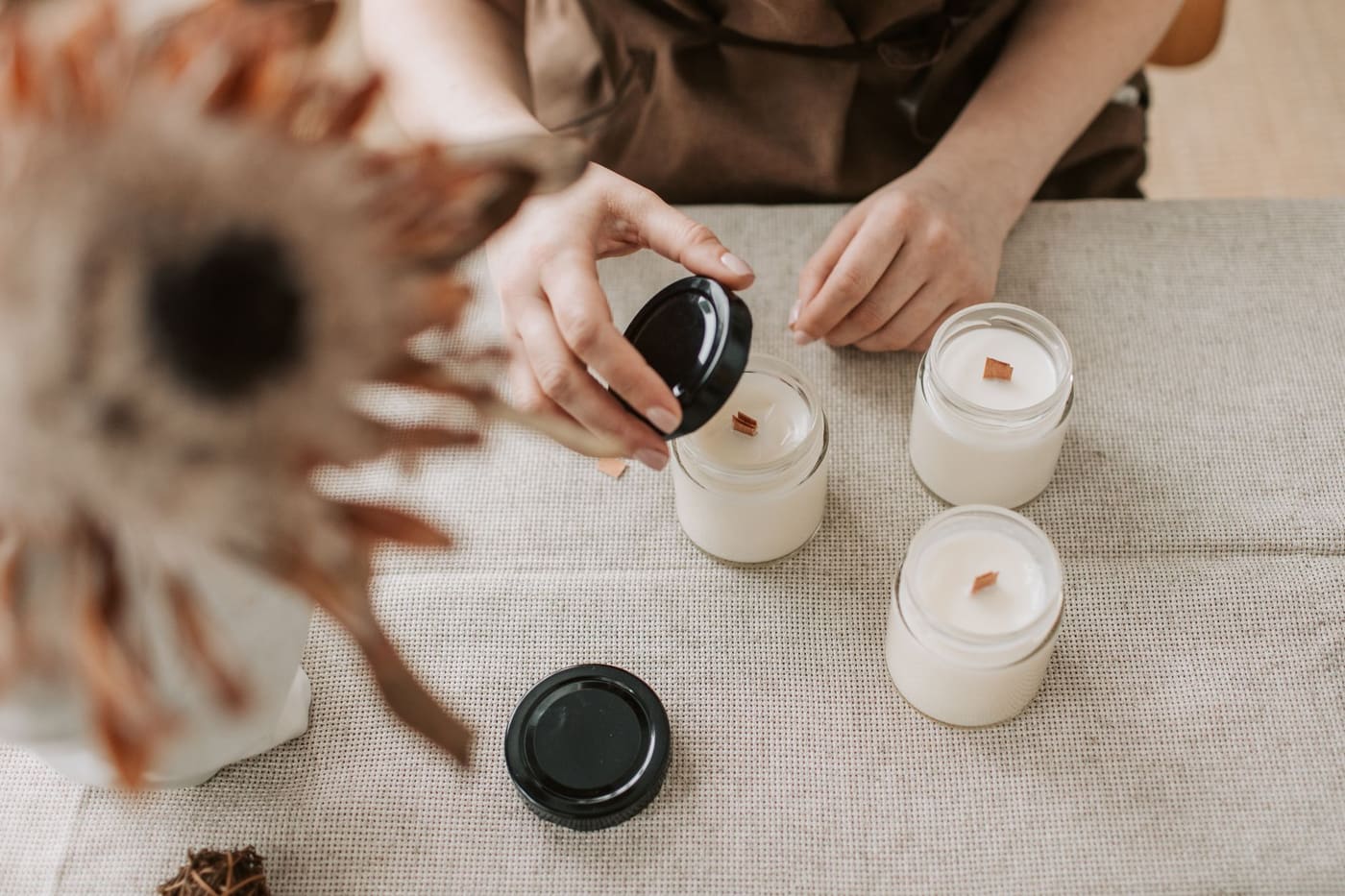 Hands making handmade candles in a small indoor workshop