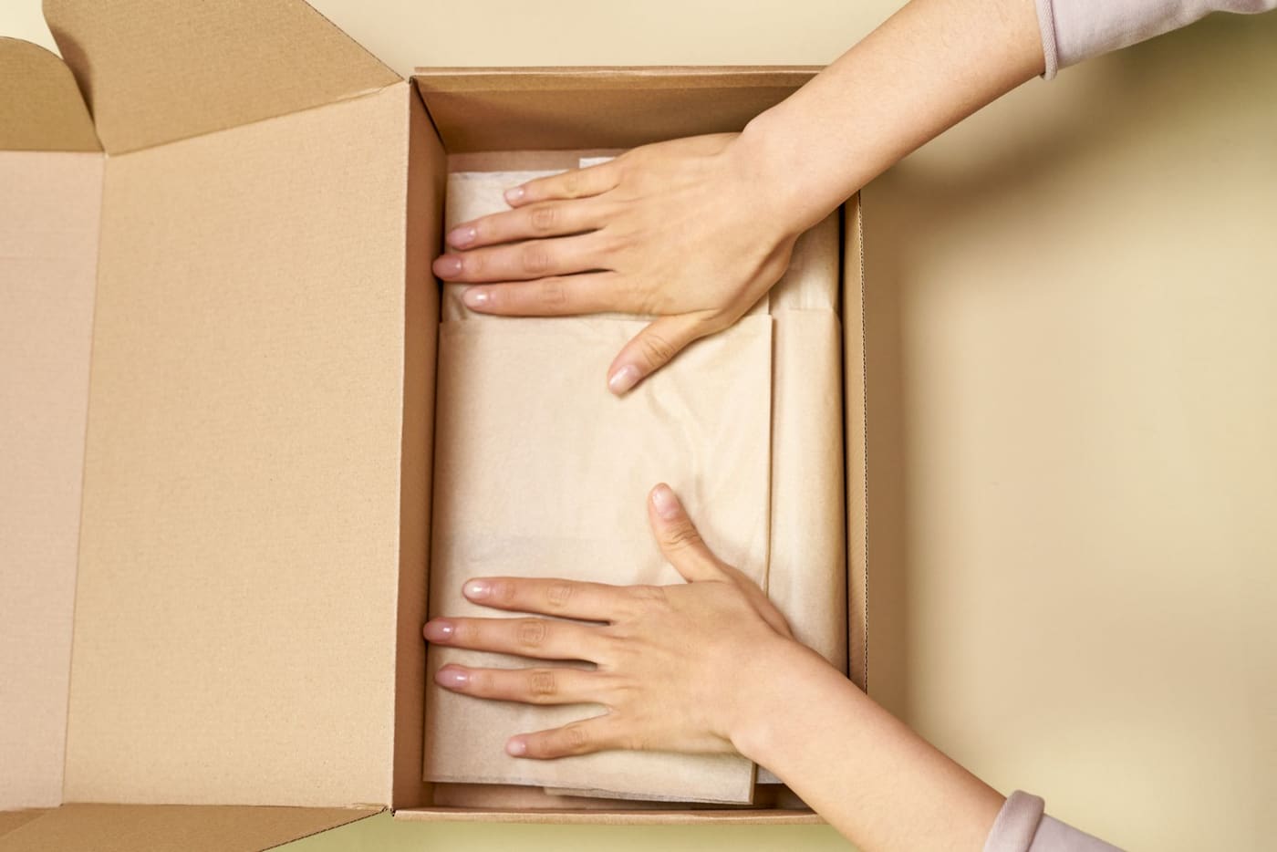 Hands pressing parchment paper into a cardboard box