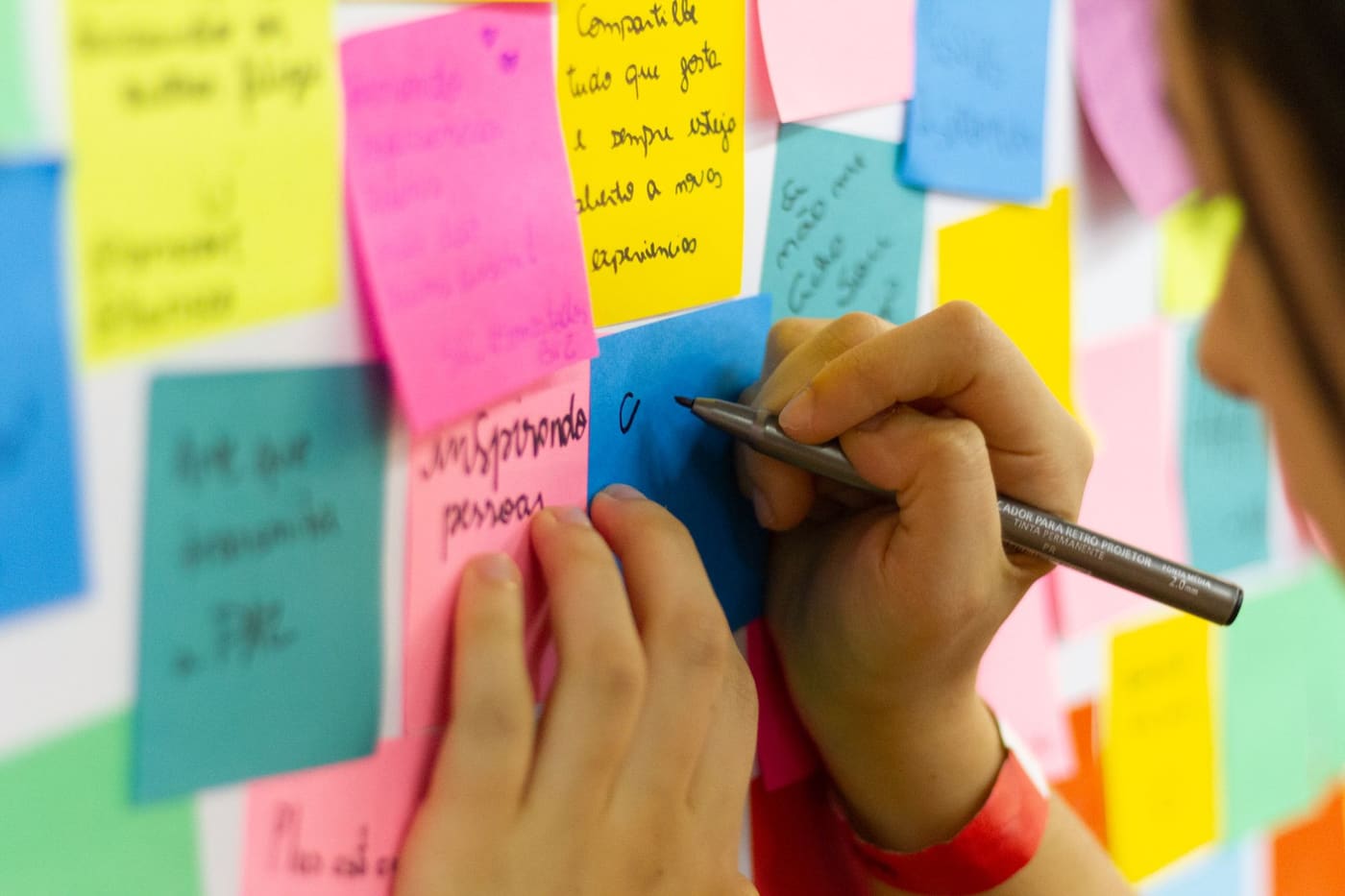 Hands writing on colorful sticky notes during a planning session