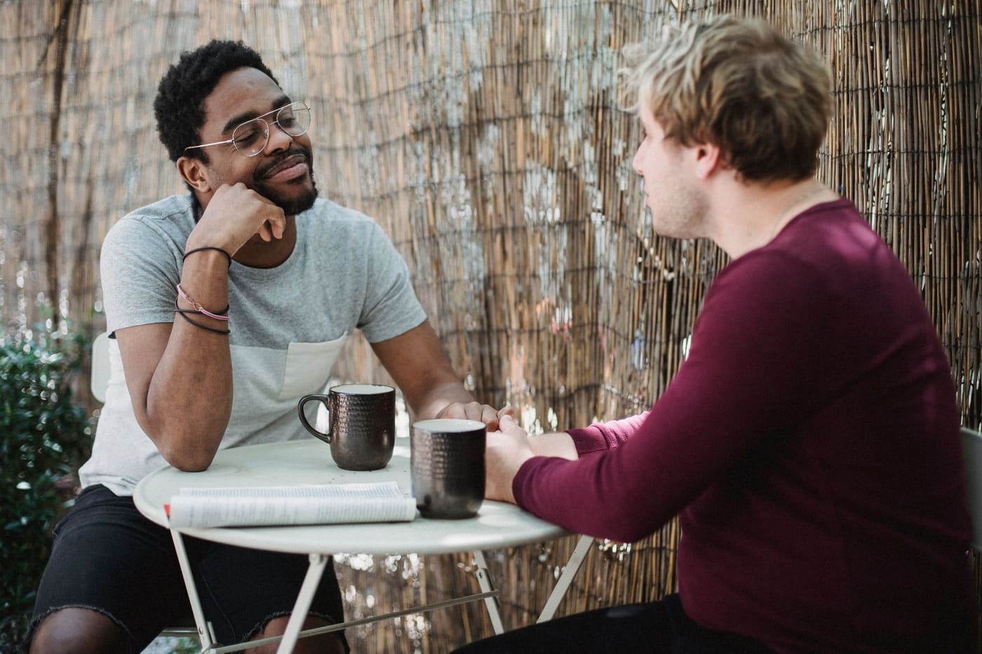 Two men talking over coffee at a small outdoor cafe table