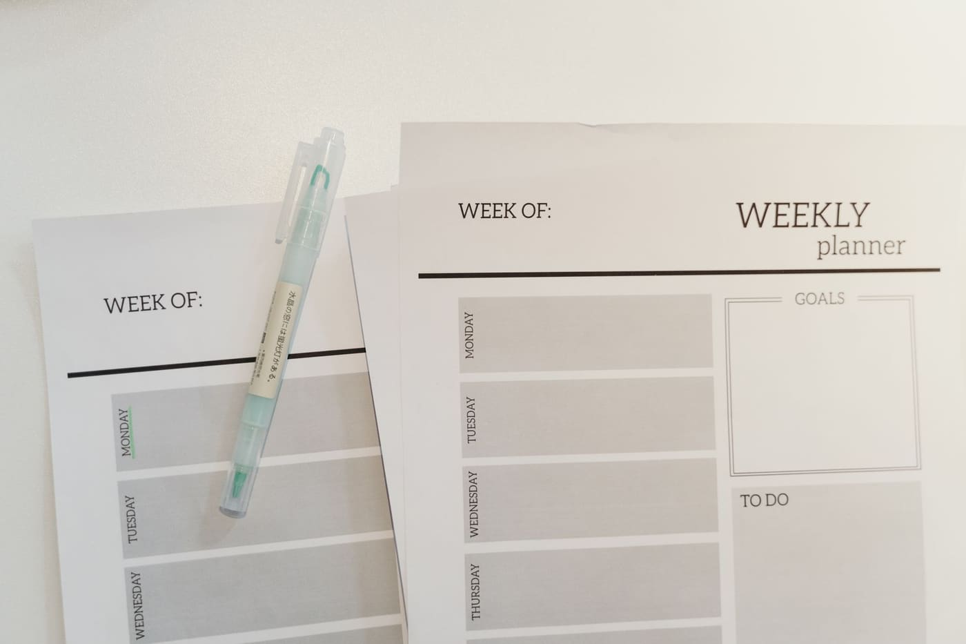Blank weekly planner sheets with a pen resting on them