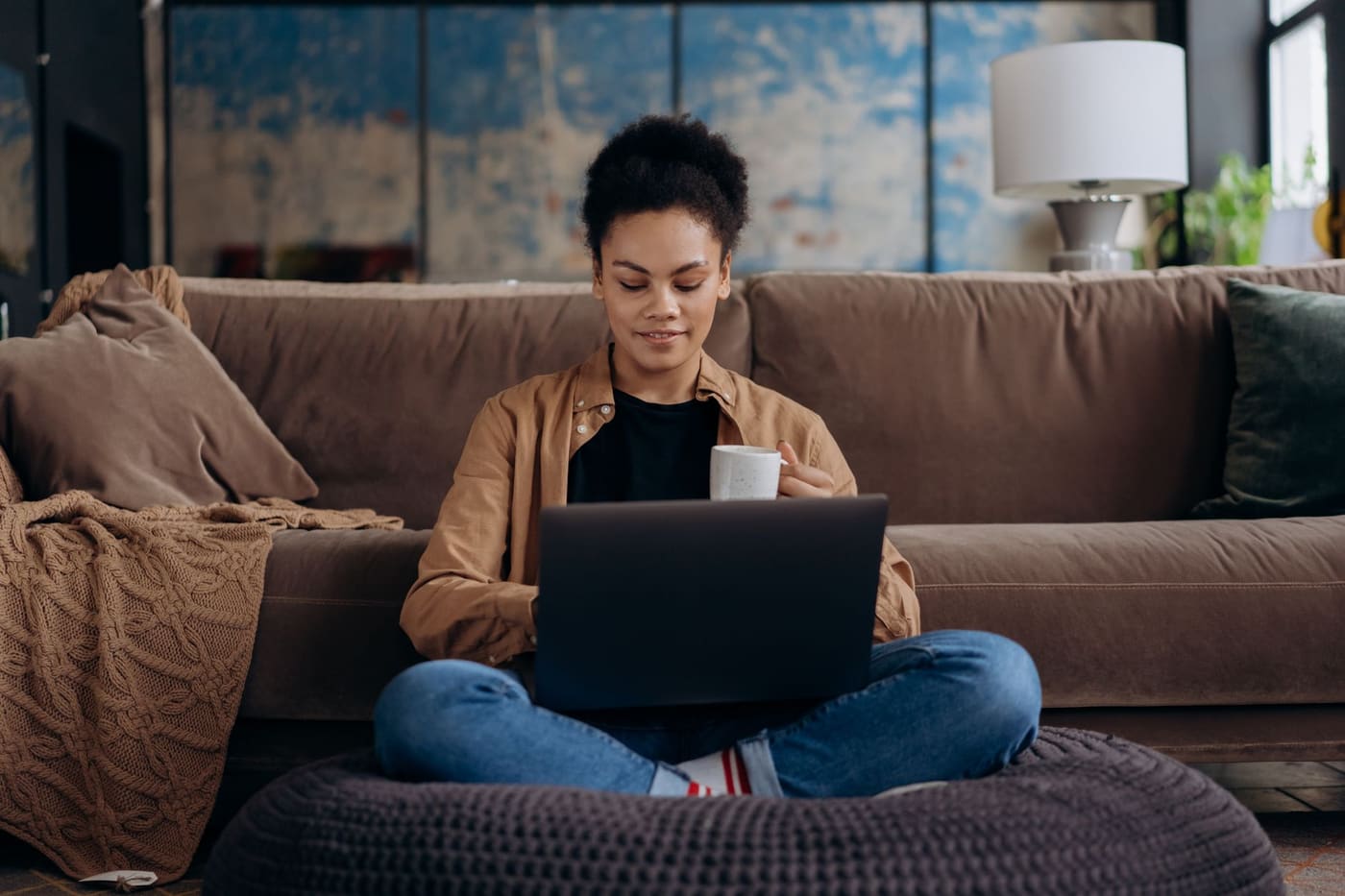 A woman sitting cross-legged on a sofa with a laptop