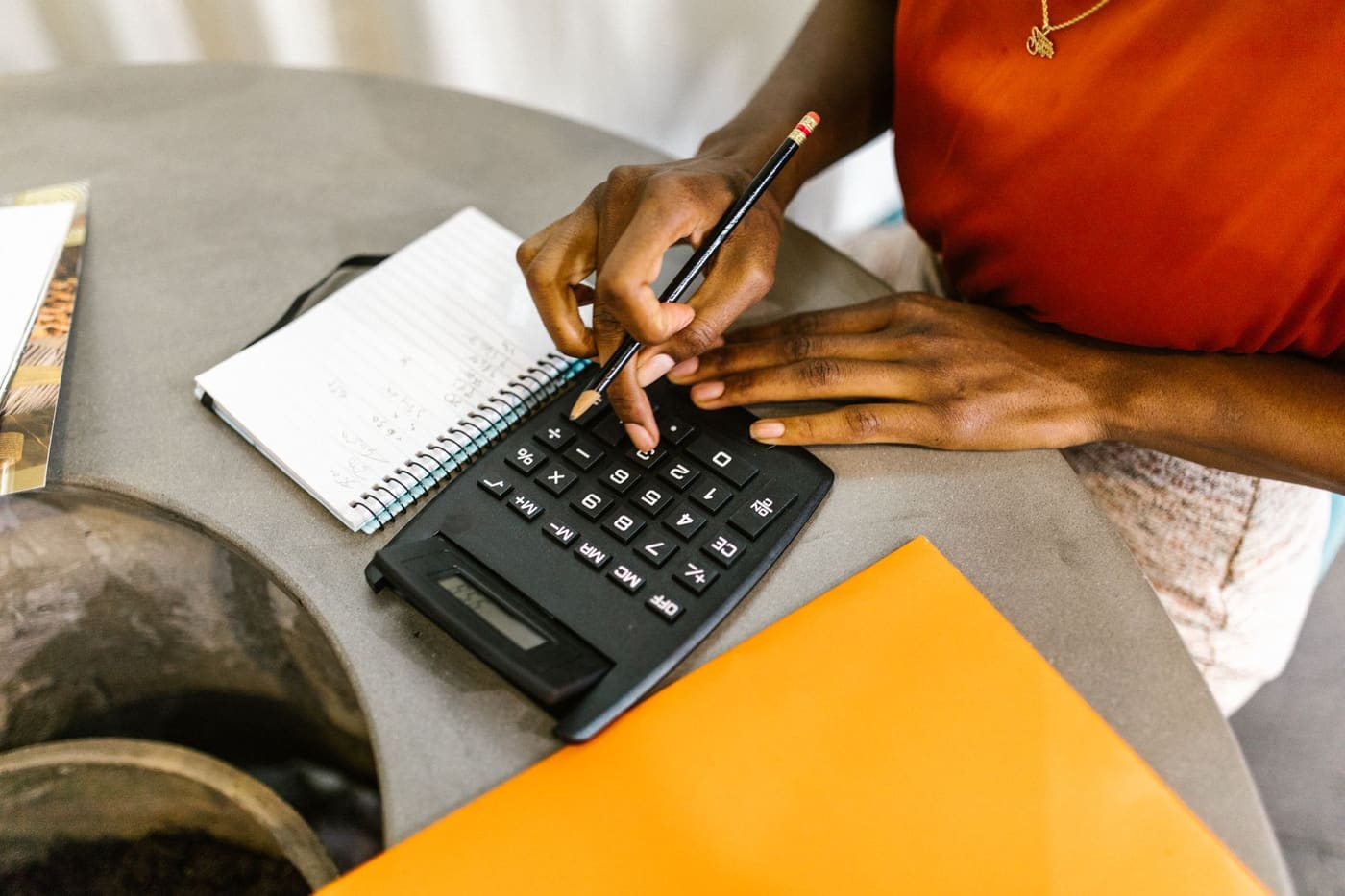 A person working out numbers on a calculator beside a notepad